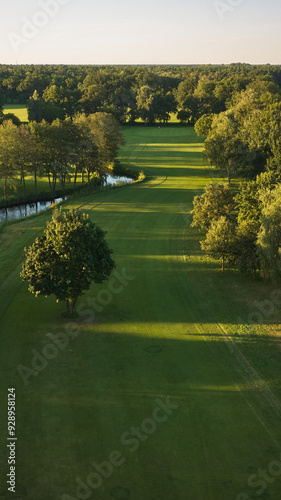 A tranquil aerial view of a lush golf course fairway, bathed in the warm glow of sunset. 