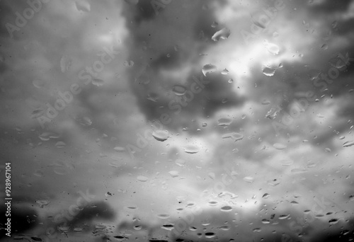 Cloudy sky seen from car window with rain drops on it. Black and white