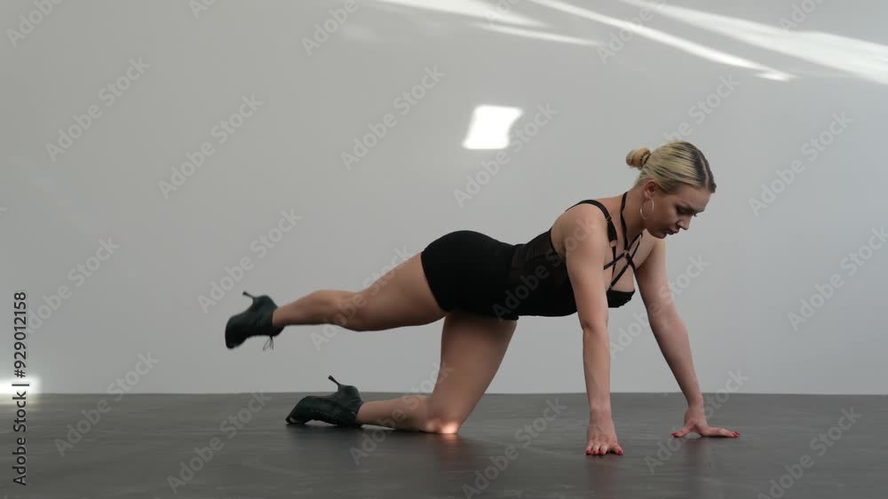 Young woman in black clothes warming up before dance rehearsal high hills in a white room with a black floor Young woman in black clothes warming up before dance rehearsal high hills in a white room with a black floor