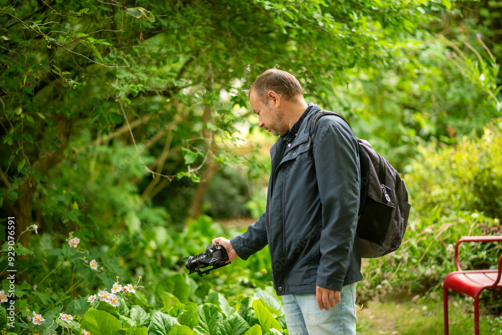 Obraz premium Man with Camera in Lush Garden Capturing Nature Photography