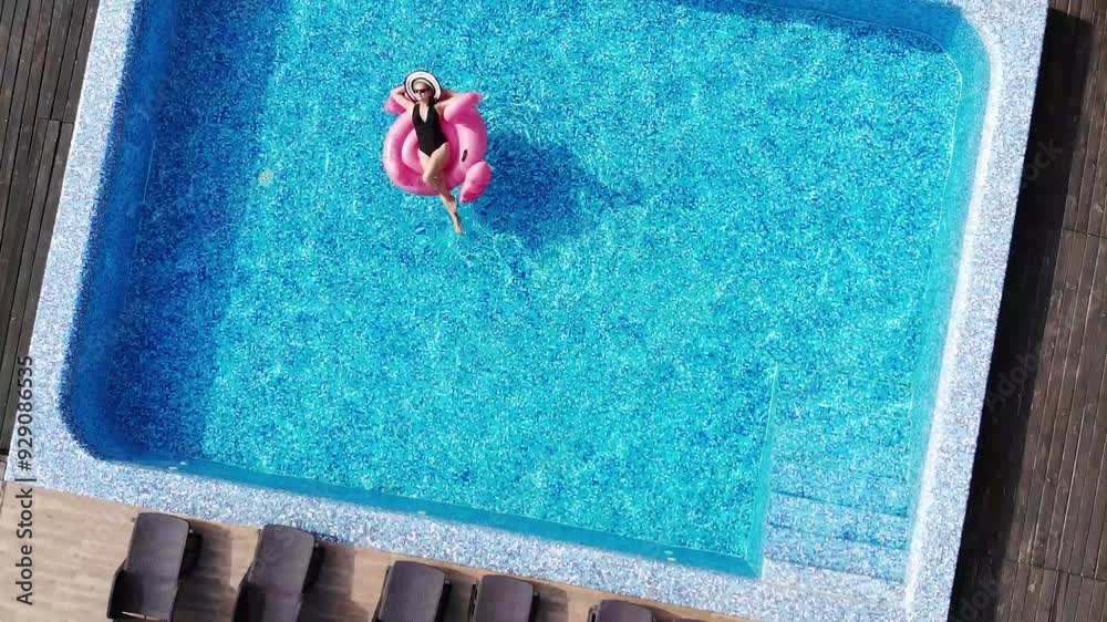 Aerial drone view of woman on pool flamingo float in pool in hotel. Summer holidays, enjoying summer vacations. Aerial drone view
