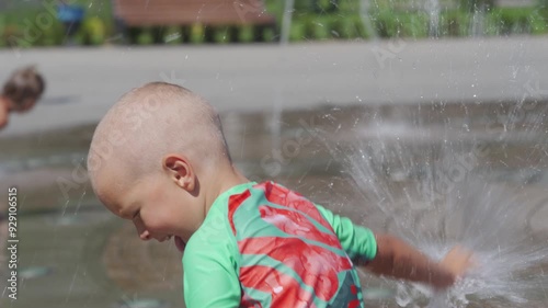 Happy wet child bathing in fountain water streams in summer. Light and music fountain on the Tereshkova embankment. Yevpatoria, Crimea 2024 photo