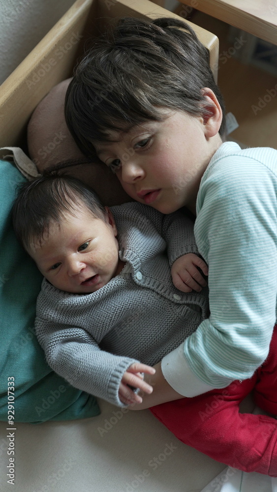 Older brother lovingly cuddles his newborn sibling, both lying comfortably on a bed, showcasing a tender moment of sibling bond and affection Older brother lovingly cuddles his newborn sibling, both lying comfortably on a bed, showcasing a tender moment of sibling bond and affection