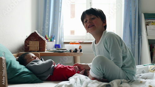 Older sibling engages with baby on a bed, creating a warm and affectionate scene in a sunlit room and toys on the table, emphasizing a loving sibling relationship