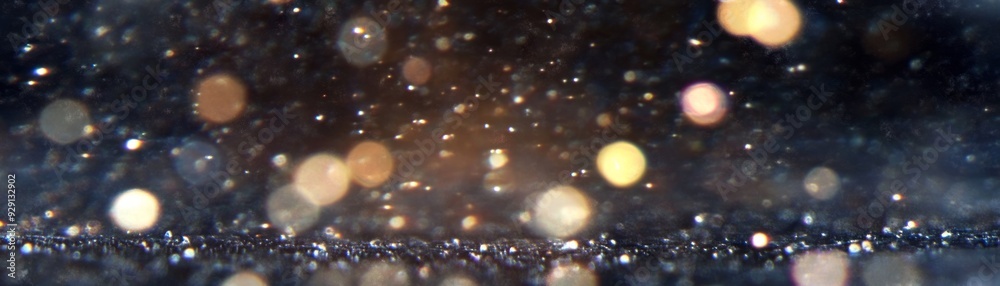 Golden particles shimmering in soft light on a dark surface Golden particles shimmering in soft light on a dark surface