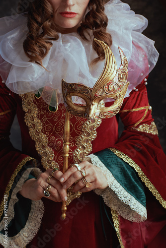 Closeup on medieval queen in red dress with venetian mask