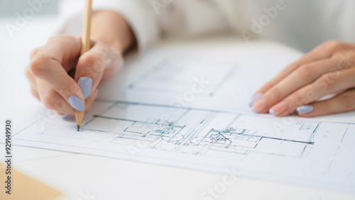 Closeup of professional caucasian female engineer hand drawing blueprint. Creative design and teamwork concept with blueprint and architectural equipments placed on table. Focus on hand. Immaculate.