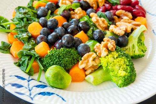 Close-up of healthy colorful diet food a tasty porton steamed and roasted vegetables topped with nuts and blueberries. Selective focus with shallow depth of field.