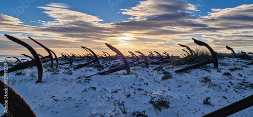 Rusty old anchors on the beach at the Anchor Cemetary graveyard at Praia do Barril beach in Tavira, Algarve, Portugal