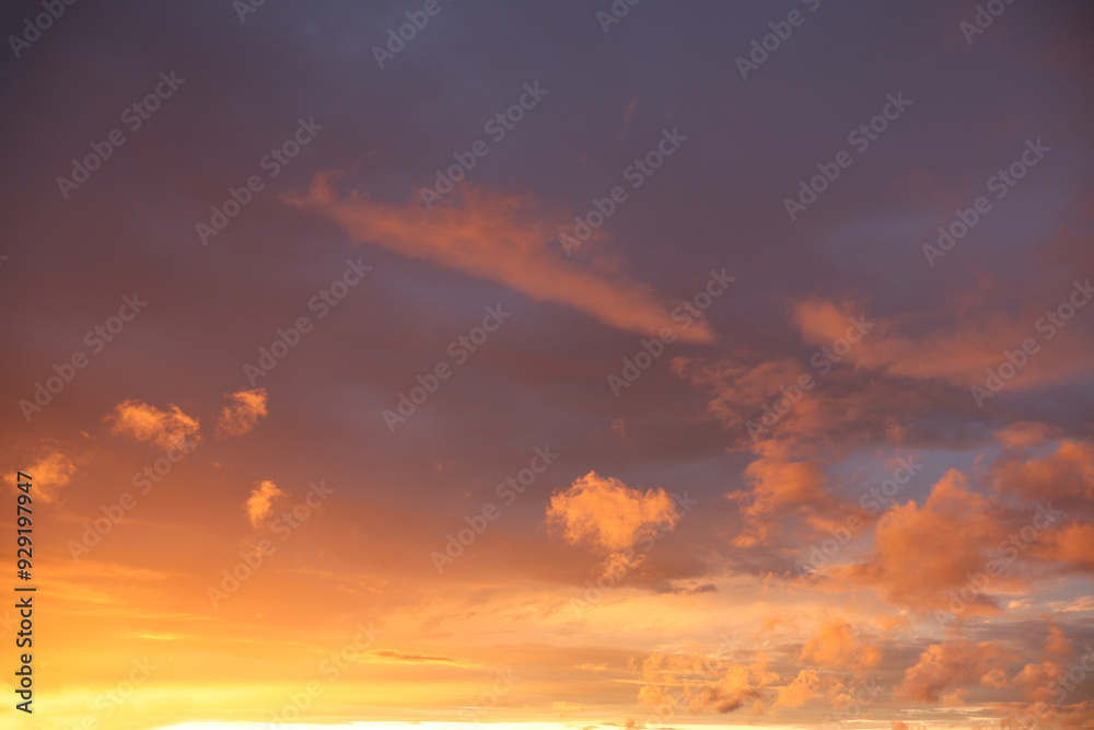 Fototapeta premium A sunset over the horizon, with delicate shades of orange and bluish, as the sun dips below the horizon. Clouds create serenity and drama to the scene.
