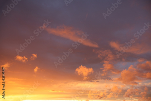 A sunset over the horizon, with delicate shades of orange and bluish, as the sun dips below the horizon. Clouds create serenity and drama to the scene.