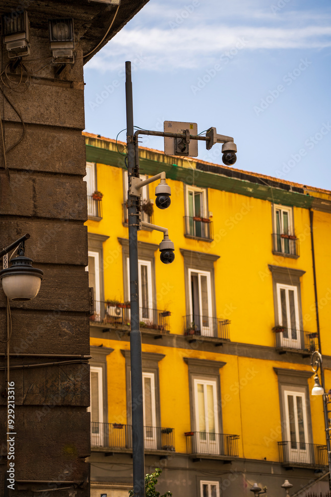 Urban Security Cameras on Vibrant Yellow Building Exterior, surveillance in Europe in outdoors in public , CCTV