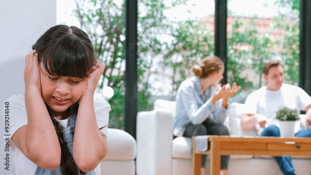 Stressed and unhappy young girl huddle in corner, cover her ears blocking sound of her parent arguing in background. Domestic violence at home and traumatic childhood develop to depression. Synchronos Stressed and unhappy young girl huddle in corner, cover her ears blocking sound of her parent arguing in background. Domestic violence at home and traumatic childhood develop to depression. Synchronos