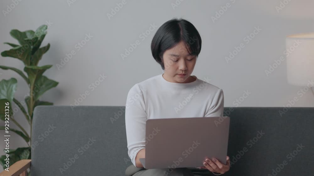 Young woman closing her laptop after completing work from home, enjoying a moment of relaxation in her living room Young woman closing her laptop after completing work from home, enjoying a moment of relaxation in her living room
