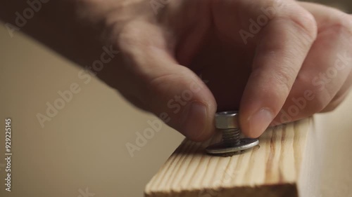A man tightens a nut with a wrench while assembling furniture. Close-up of his hands