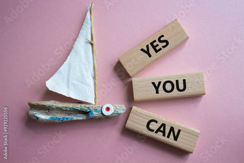 Yes You Can symbol. Concept word Yes You Can on wooden blocks. Beautiful pink background with boat. Business and Yes You Can concept. Copy space.