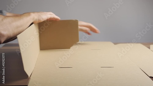 Man folding cardboard box for packing goods. Hands close-up
