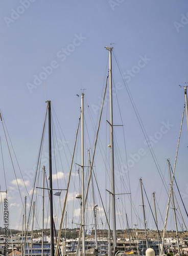 Empty masts of sailboats against a cloudless sky