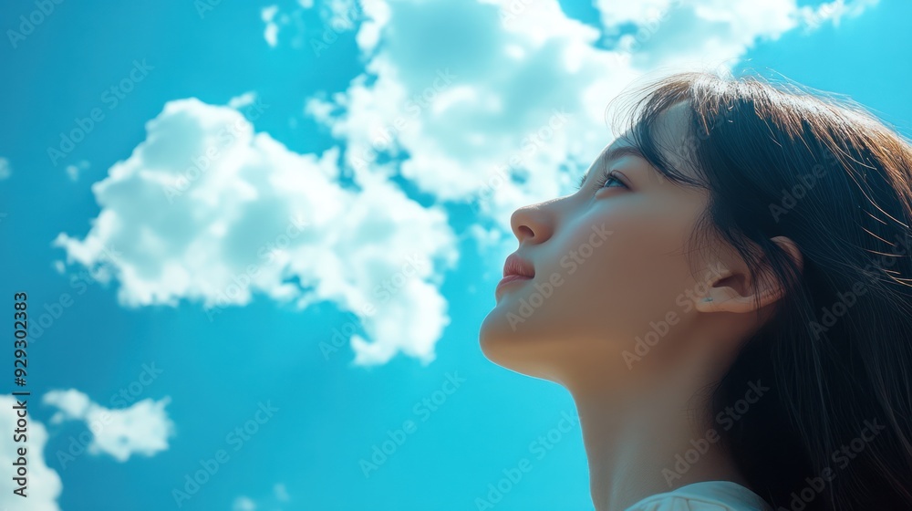 A serene young woman gazes thoughtfully at the sky, surrounded by fluffy clouds, evoking a sense of peace and contemplation. A serene young woman gazes thoughtfully at the sky, surrounded by fluffy clouds, evoking a sense of peace and contemplation.