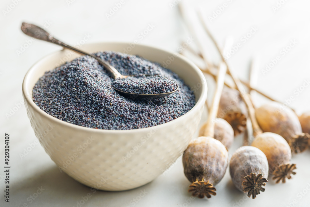 Obraz premium Dry poppy head and poppy seed in bowl on kitchen table.