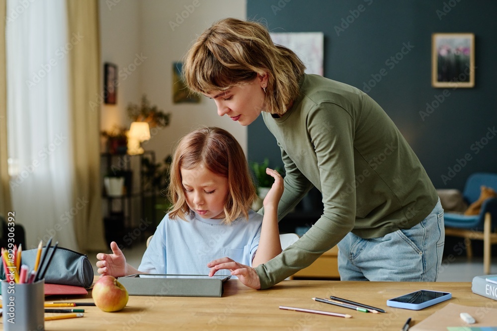 Fototapeta premium Young Caucasian mom helping her daughter to gain new level in video game