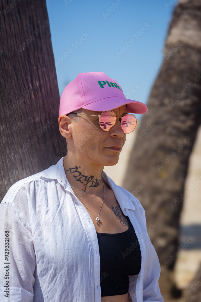 Cancer survivor in pink cap standing by a tree on a sunny beach Cancer survivor in pink cap standing by a tree on a sunny beach