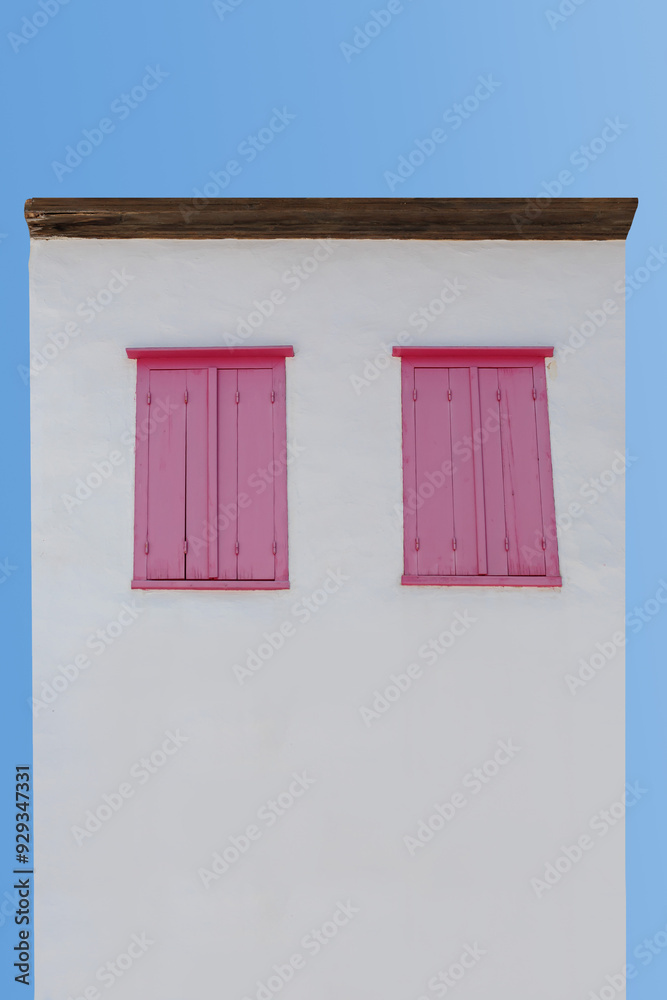 white building with pink wooden shutters against a blue sky white building with pink wooden shutters against a blue sky