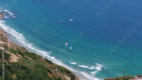 Aerial view of paragliders flying over Blacks Beach by Scripps Pier in La Jolla San Diego on a sunny day with blue sky and blue Pacific Ocean in Southern California photo