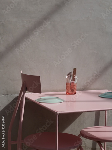 Cafetería con pared de concreto, mesas rosas y platos de colores pastel  photo