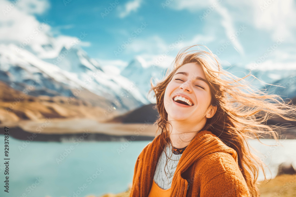A joyful woman with windswept hair savors a moment of freedom and happiness against a breathtaking mountain and lake backdrop.