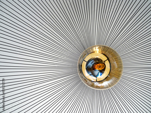 Abstract image of a suspending light with yellow bumb and black metalic lines. Monocrome background lines. close-up photo