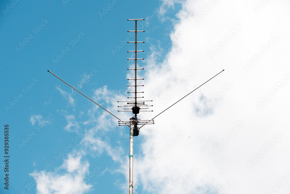 A large antenna stands out against a blue sky with fluffy clouds A large antenna stands out against a blue sky with fluffy clouds