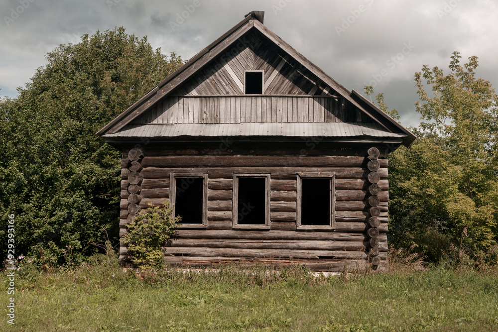 An old log cabin is situated in the middle of a grassy field An old log cabin is situated in the middle of a grassy field