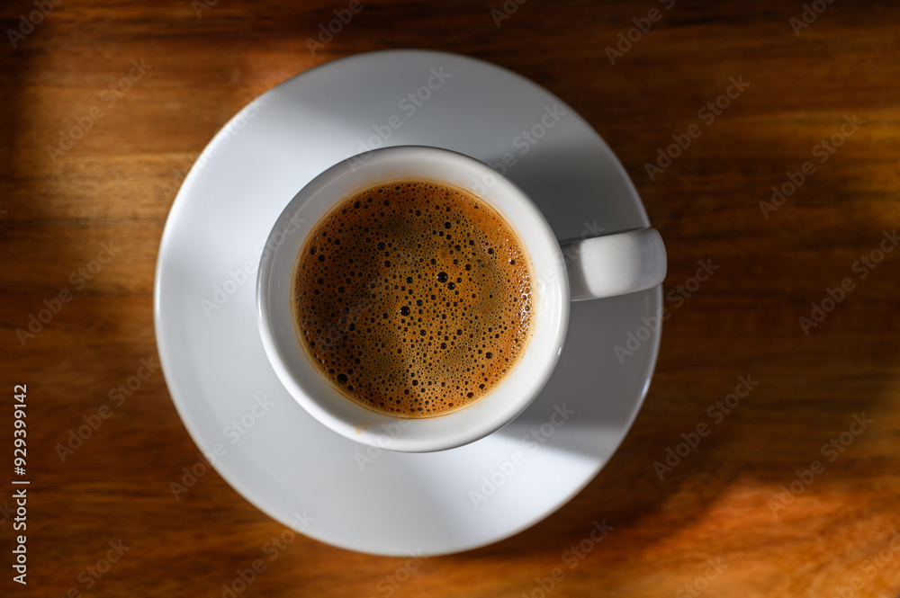 A cup of coffee sits on a wooden table A cup of coffee sits on a wooden table