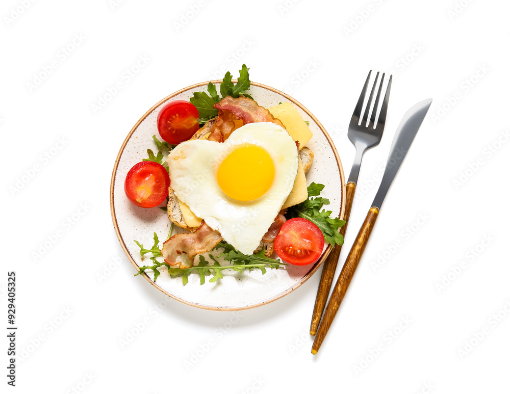 Toast with fried egg, bacon, tomatoes, arugula in plate and cutlery on white background Toast with fried egg, bacon, tomatoes, arugula in plate and cutlery on white background