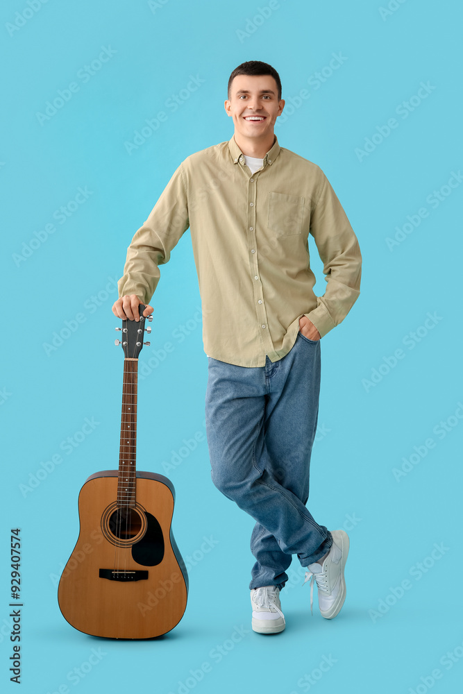 Naklejka premium Handsome young man with guitar on blue background
