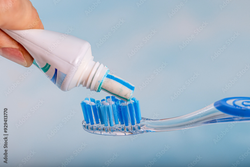 Toothbrush and toothpaste, Squeezing toothpaste onto toothbrush. Applying toothpaste on brush against blurred background, closeup. Toothbrush and toothpaste, Squeezing toothpaste onto toothbrush. Applying toothpaste on brush against blurred background, closeup.