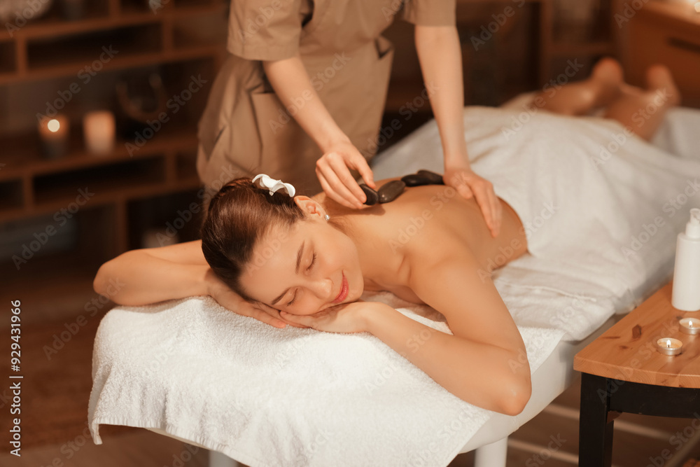 Obraz premium Beautiful woman getting massage with stones on couch in dark spa salon