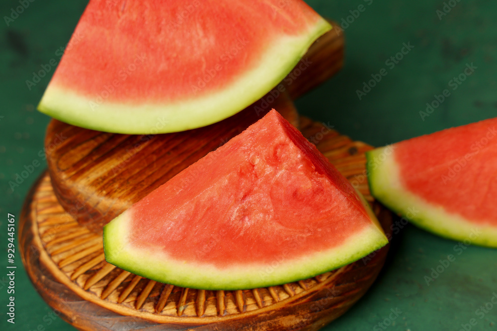 Wooden boards with pieces of sweet watermelon on green background