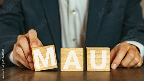 There is wood cube with the word MAU. It is an abbreviation for Monthly Active Users as eye-catching image.