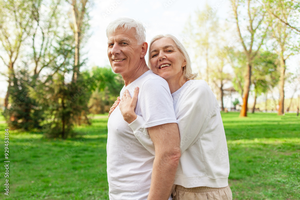 elderly couple of seniors man and woman hugging and smiling in the park outdoors, gray-haired grandparents in white T-shirts in nature elderly couple of seniors man and woman hugging and smiling in the park outdoors, gray-haired grandparents in white T-shirts in nature