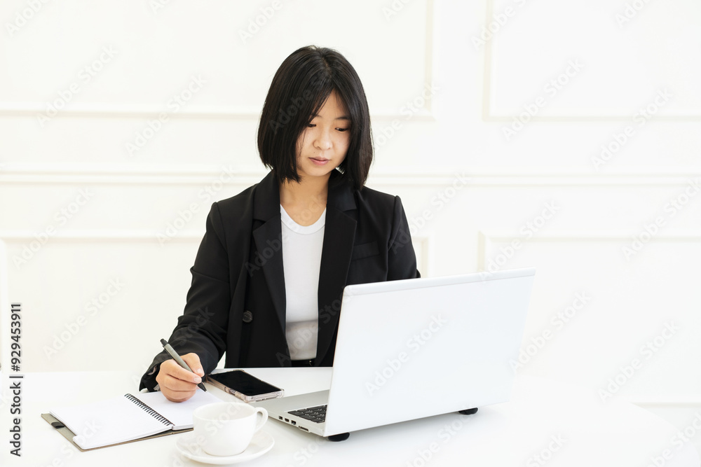 Asian woman typing on laptop in her apartment front view, work from home concept. Asian woman typing on laptop in her apartment front view, work from home concept.