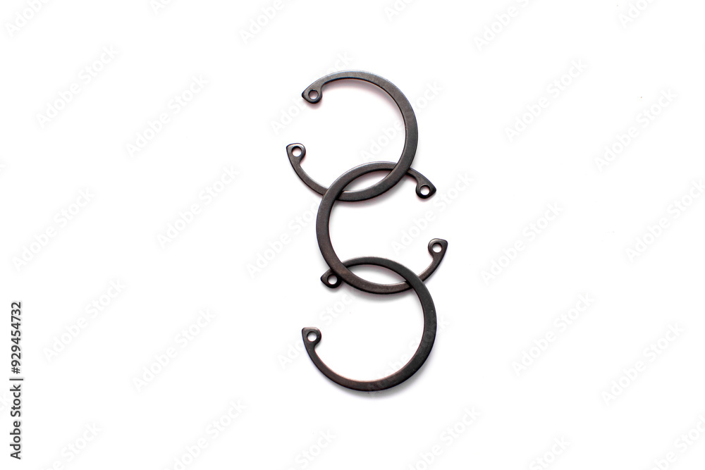 Black circlip retaining rings scattered on a white background. Black circlip retaining rings scattered on a white background.