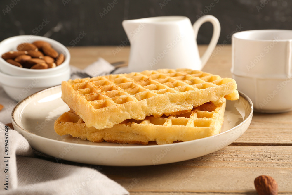 Plate with tasty Belgian waffles, almond and cup of coffee on wooden table Plate with tasty Belgian waffles, almond and cup of coffee on wooden table