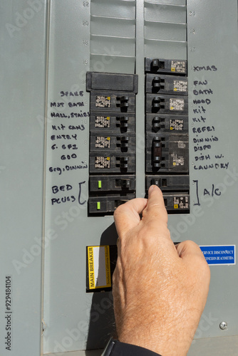 Man's hand resetting tripped circuit breaker in outdoor electrical panel