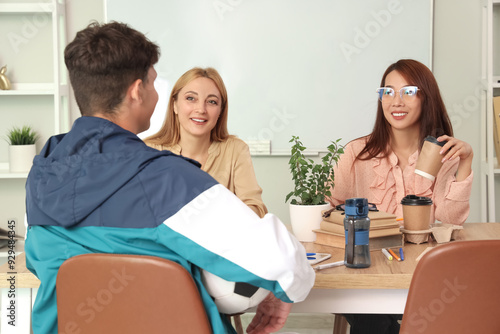 Teachers with coffee sitting at table in school office