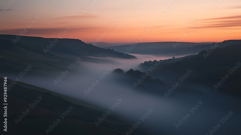 A long exposure shot of moving fog in a valley at dawn, with a faint orange glow from the rising sun