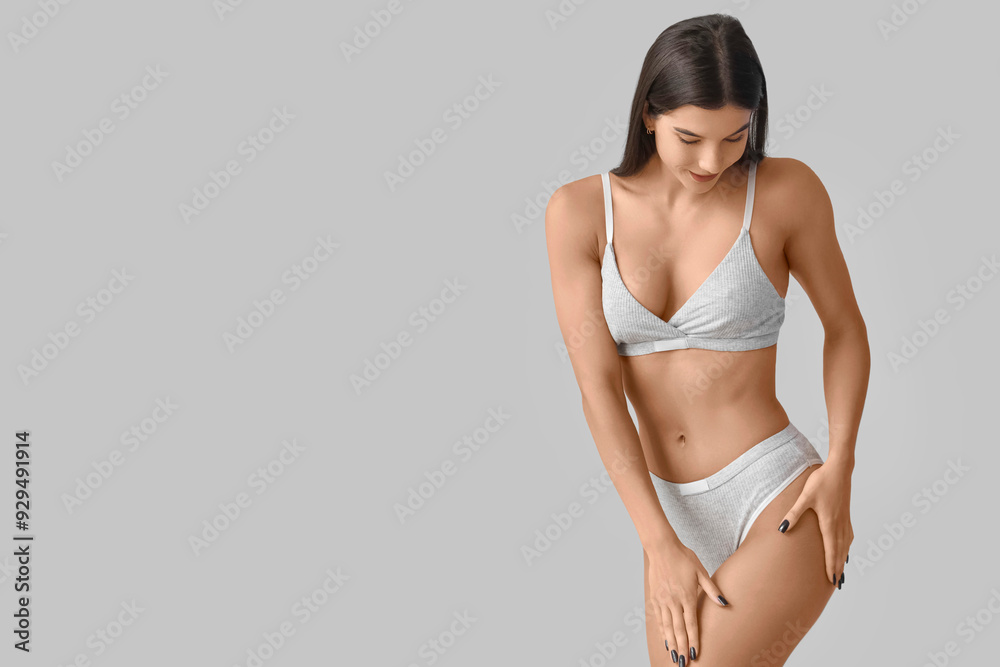 Fototapeta premium Young woman in underwear with cellulite problem on light background