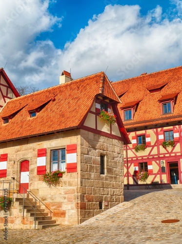 Traditional german architecture, charming half timbered houses with red roofs and cobblestone street on a sunny day