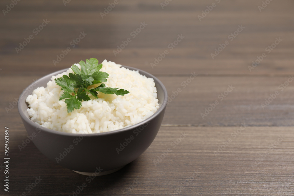 Bowl of delicious boiled rice with parsley on wooden table. Space for text Bowl of delicious boiled rice with parsley on wooden table. Space for text